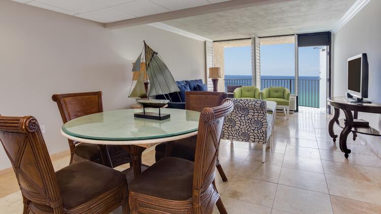 Dining room table, living room, TV, and view of balcony overlooking gulf