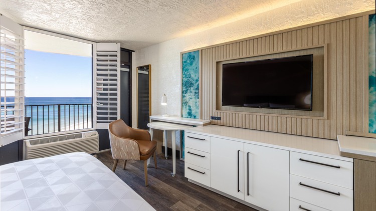 Mounted TV on wall with white cabinets and view of ocean from balcony