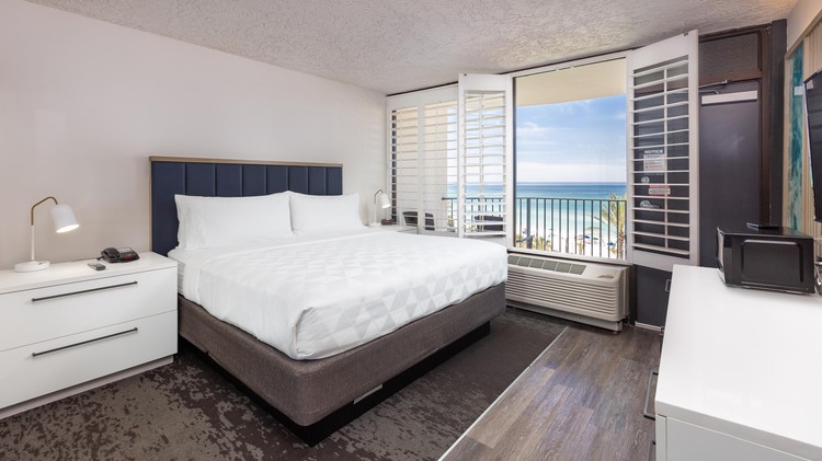 King bed with view of balcony and ocean beside white side table