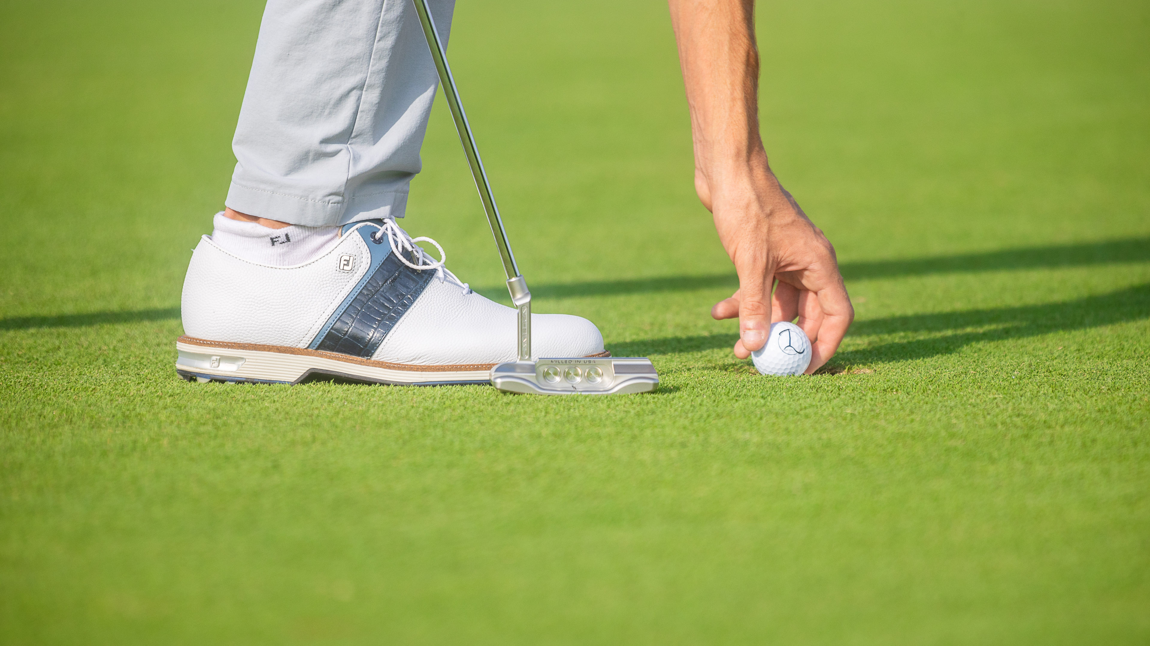 Golfer taking a golfball from the hole