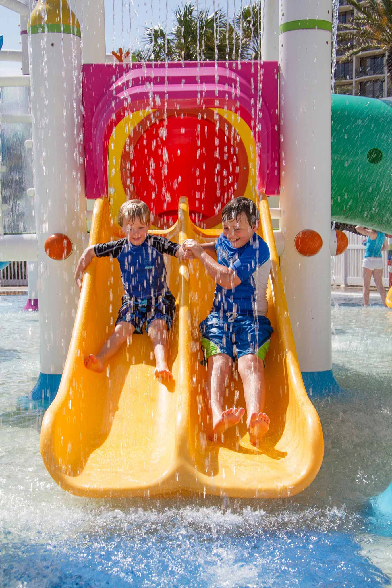 Kids sliding down water slide and landing in pool